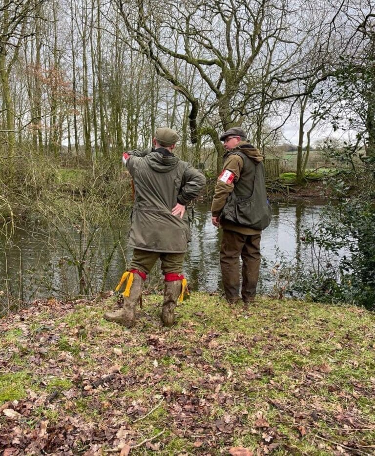 Two trainers having a chat by a river in a forest