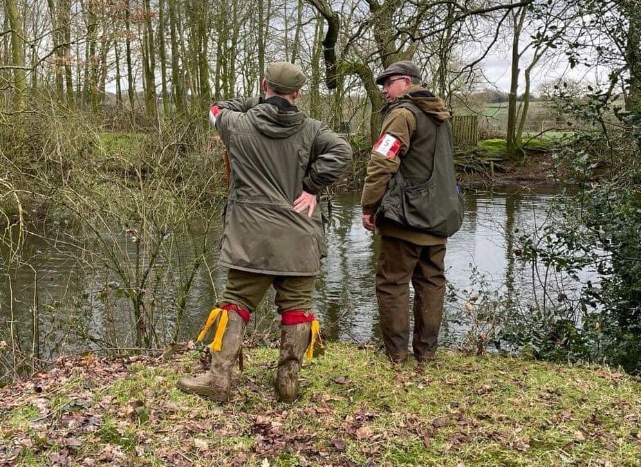 Two trainers having a chat by a river in a forest